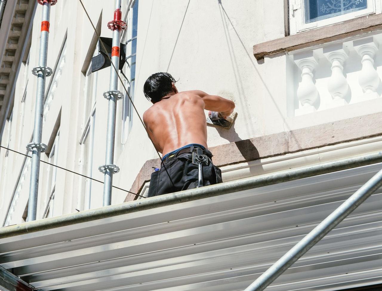 man in black shorts sitting on white metal bar during daytime